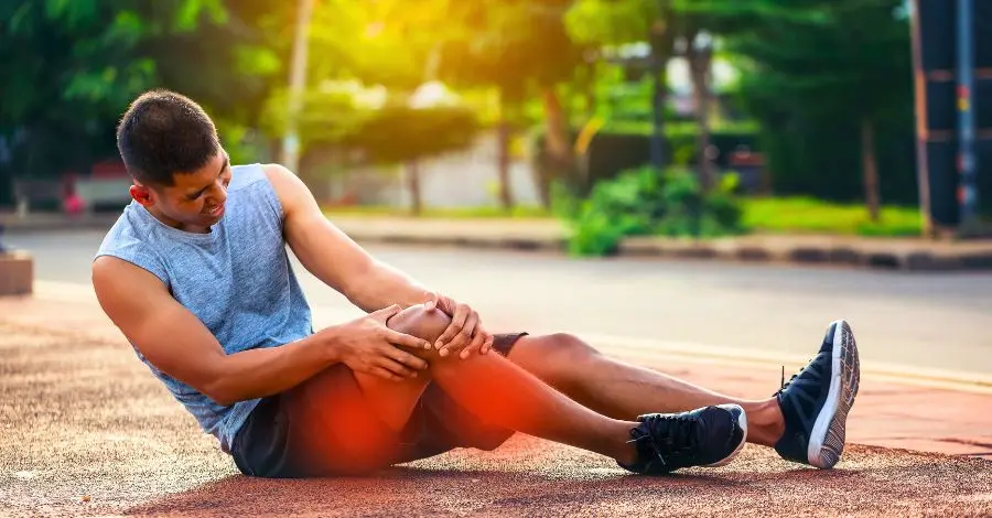 Homem sentindo dor muscular pós-treino na perna, sintoma de dor muscular tardia (DOMS).