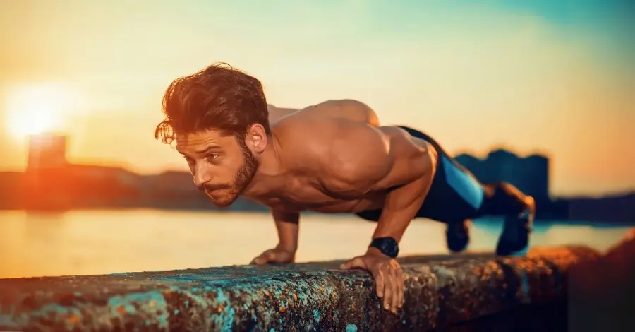 Homem realizando flexão de braços (push-up), um exercício com peso corporal para fortalecer peito, ombros e tríceps, e ativar o core.